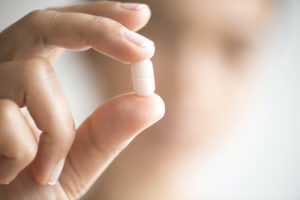 Woman holding medication capsule.