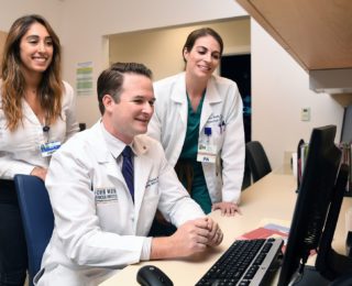 Doctors talking around computer