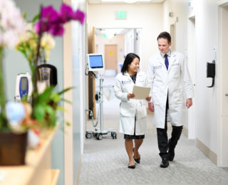 Doctors looking at chart while walking through hallway