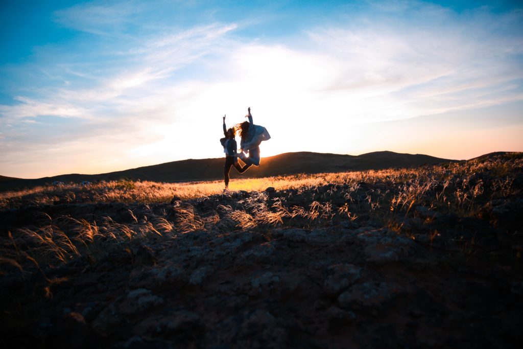two women jumping in the field